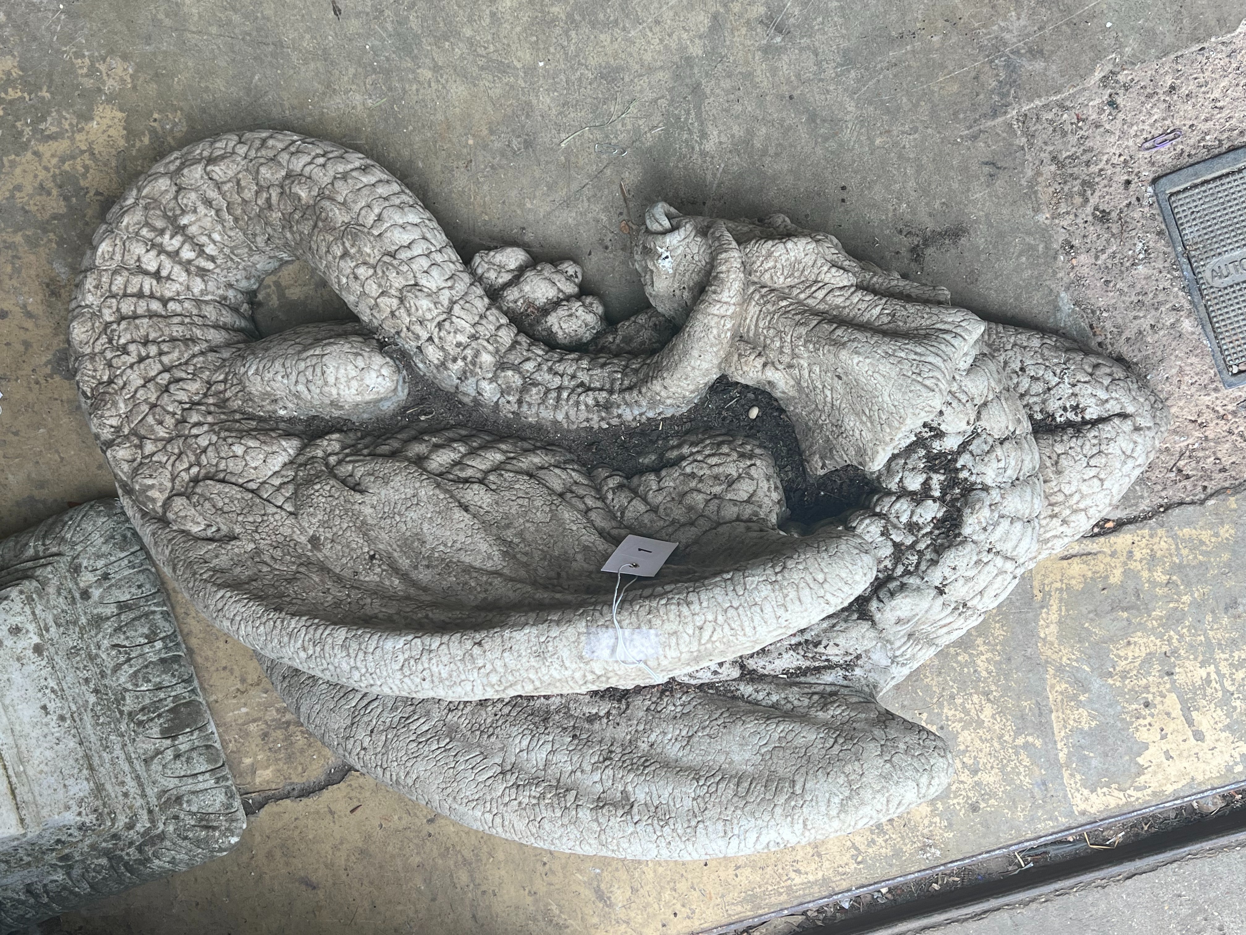 A reconstituted stone garden ornament of a sleeping dragon, width 80cm